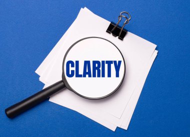 Mavi arka planda, siyah bir ataçın altındaki beyaz çarşaflar ve üzerinde CLARITY metni olan bir büyüteç.