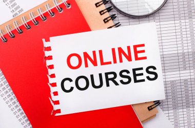 Hafif bir arkaplanda - raporlar, bir büyüteç, kahverengi ve kırmızı not defterleri ve ONLINE COURSES yazılı beyaz bir not defteri. İş konsepti
