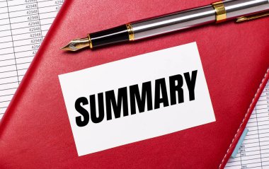 Masaüstünde raporlar, bordo bir defter, bir dolmakalem ve içinde SUMMARY yazılı beyaz bir kart var. İş konsepti