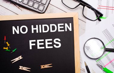 Masaüstünde bir hesap makinesi, raporlar, gözlükler, bir büyüteç, kalemler ve mandallı bir pano ve HAYIR gizli ödemeleri var. İş konsepti.