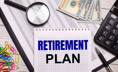 Ofis masasında içinde RETIREMENT PLAN yazan bir defter, bir kalem, bir hesap makinesi, dolar, renkli ataçlar ve bir büyüteç var. Şık bir iş yeri. İş konsepti