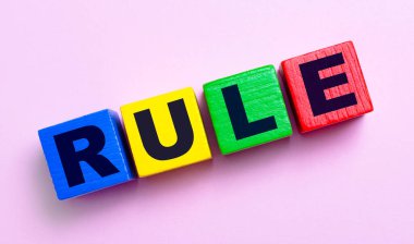 Açık pembe arka planda, metin kurallı çok renkli ahşap küpler
