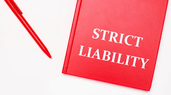 STRICT LIABILITY, ofisteki beyaz bir masada kırmızı bir kalem yakınında kırmızı bir not defterine yazılmıştır. İş konsepti