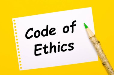 Parlak sarı bir arka planda, büyük tahta bir kalem ve üzerinde ETHICS 'in metni olan beyaz bir sayfa.
