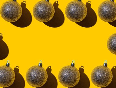 Parlak sarı arka planda, yazıyı koyacak bir yeri olan altın renkli Noel topları çerçevesi. Noel ve Yeni Yıl tatili geçmişi