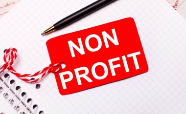 Beyaz bir defter üzerinde siyah bir kalem ve kırmızı fiyat etiketi var NON PROFIT metni ile bir dizgi üzerinde