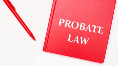 PROBATE LAW metni kırmızı bir not defterine yazılmıştır. Ofisteki beyaz bir masada kırmızı bir kalem yanında. İş konsepti