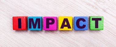 Açık ahşap arka planda, IMPACT yazılı çok renkli ahşap küpler