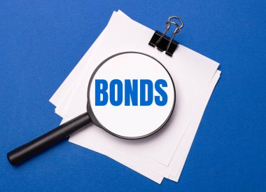 Mavi arka planda, siyah bir ataçın altındaki beyaz çarşaflar ve onların üzerinde de BONDS yazılı bir büyüteç.