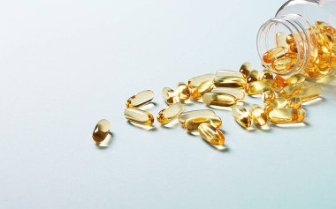 Açık mavi arka planda, Omega-3 kapsüllü açık bir şişe. Tıbbi konsept. Boşluğu kopyala