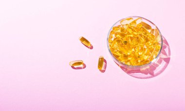 Pembe arka planda duran Omega-3 kapsülleri. Balık yağı tabletleri. Sağlık desteği ve tedavi. Biyolojik olarak aktif katkı maddeleri. Seçici odak.