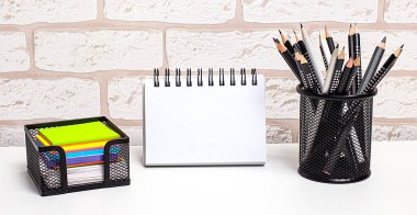 Evde parlak çıkartmaları olan bir işyeri, stantta kalemler ve tuğla duvara yazı yapıştıracak temiz bir defter. Merkez ofis. İş yeri, yakın çekim. Model