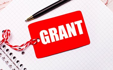 Beyaz bir defterde siyah bir kalem ve üzerinde GRANT metni olan bir dizgi üzerinde kırmızı bir fiyat etiketi var.