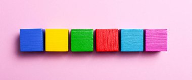 Açık pembe arka planda, çok renkli tahta küplerin arasına bir metin eklemek için bir sıra. Uzayı kopyala Model