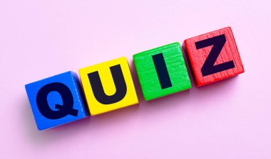 Açık pembe arka planda, QUIZ yazılı çok renkli ahşap küpler