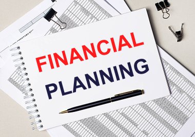 Masaüstünde belgeler, kalem, siyah ataç ve içinde FINANCIAL PLANNING metni olan bir defter var. İş konsepti