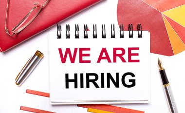 Masaüstünde beyaz bir defter var. Kiraladığımız metin, kalem, bordo ve kırmızı masalar ve altın çerçeveli gözlükler. İş konsepti.