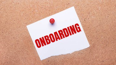 Beyaz kağıt üzerinde ONBOARDING kırmızı bir düğme ile ahşap zemin eklenmiş.