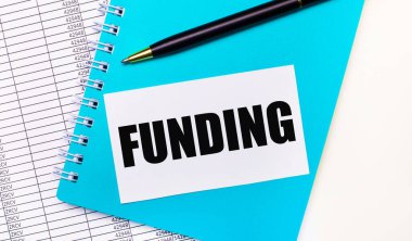 Ofis masasında raporlar var, mavi bir not defteri, siyah bir kalem, ve üzerinde yazı yazan beyaz bir kart. Şık bir iş yeri. İş konsepti