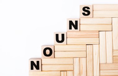 Hafif bir arkaplanda, tahta bloklar ve NOUNS yazılı küpler