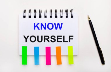 Hafif bir arkaplanda, bir kalem, içinde metin olan bir defter kendinizi tanıyın ve parlak çıkartmalar.