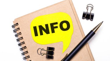 Hafif bir arka planda, kahverengi bir defter, siyah bir kalem ve ataç ve içinde INFO yazan sarı bir kart. İş konsepti.