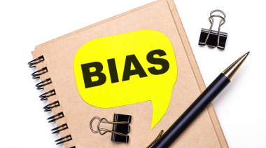 Hafif bir arkaplanda kahverengi bir defter, siyah bir kalem ve ataç ve BIAS yazılı sarı bir kart. İş konsepti.