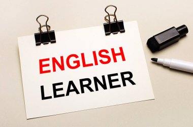 Hafif bir arkaplanda, siyah bir açık işaret ve siyah ataçlar üzerinde ENGLISH LEARNER metni olan beyaz bir sayfa