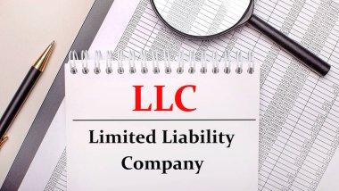 Masaüstü büyüteci, raporlar, LLC Sınırlı Borç Şirketi yazılı kalem ve defter. İş konsepti