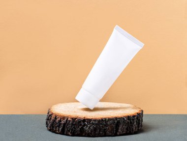 Krema için beyaz bir tüp doğal ahşap bir kürsüye eğilmiştir. Ekolojik kavram. Metin eklenecek yer. Şablon. Kopyalamak için yer var. Güzellik