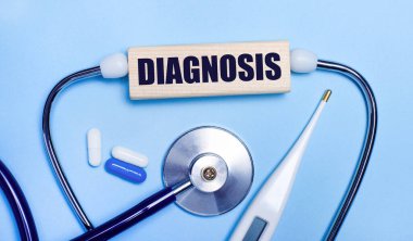 Açık gri arka planda, stetoskop, elektronik termometre, haplar, diAGNOSIS yazılı tahta blok. Tıbbi konsept.