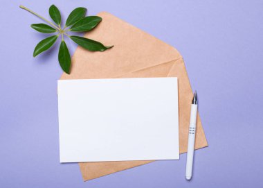 Beyaz bir kalem, saksı bitkisi, bir iğne işi zarfı ve mor üzerine yazı yazılacak beyaz bir kart. Üst Manzara. Şablon