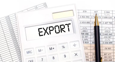 Masaüstünde raporlar var, skorbordunda EXPORT yazılı beyaz bir hesap makinesi ve bir kalem. İş konsepti.
