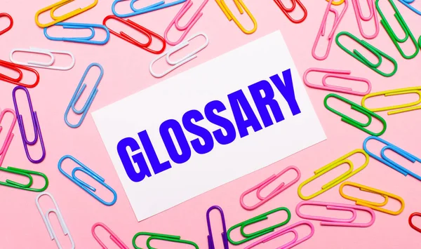 Açık Pembe Arkaplanda Renkli Parlak Ataçlar Glossary Yazılı Beyaz Bir Stok Resim