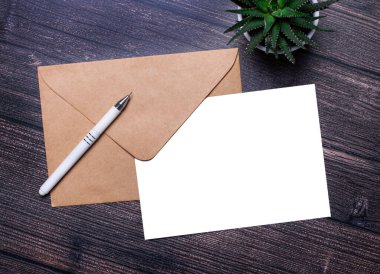 Koyu mermer bir arka planda, bir el işi zarfı, bir bitki yaprağı, bir kalem ve bir beyaz kağıt, içine yazı eklenecek bir yer. Şablon. Boşluğu kopyala