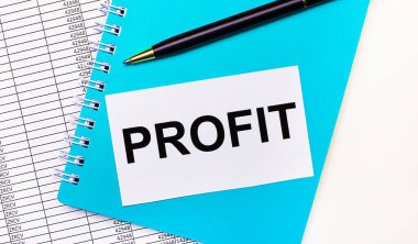 Ofis masasında raporlar, mavi bir not defteri, siyah bir kalem ve içinde PROFIT yazan beyaz bir kart var. Şık bir iş yeri. İş konsepti