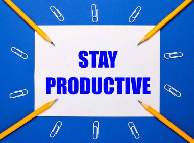 Mavi arka planda, beyaz ataçlar, sarı kalemler ve üzerinde KALDIRMA YASAK yazan beyaz bir kağıt.