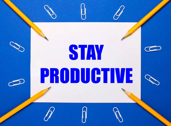 Mavi arka planda, beyaz ataçlar, sarı kalemler ve üzerinde KALDIRMA YASAK yazan beyaz bir kağıt.