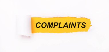 Parlak sarı bir zemin üzerinde, yırtık çizgili beyaz kağıt ve yazıt COMPLAINTS