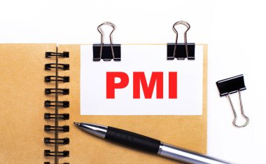 Hafif arkaplanda, kalem, siyah ataç ve PMI Proje Yönetim Enstitüsü yazılı beyaz kart içeren kahverengi bir defter