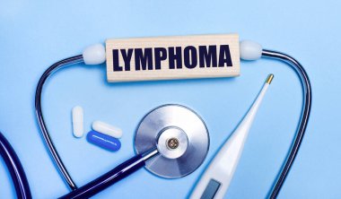 Açık gri arka planda, stetoskop, elektronik termometre, haplar, LYMPHOMA yazılı tahta blok. Tıbbi konsept.