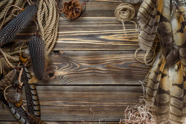 Ahşap bir arka plandaki baykuş tüyleri, bir ip ve dikiş için diğer dekorlarla birlikte.
