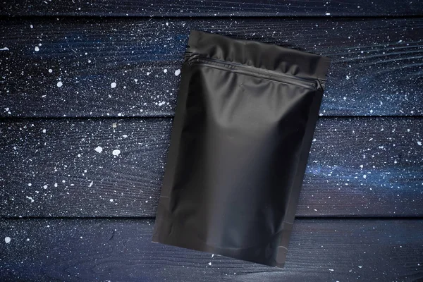 Ahşap arkaplanda zip kilidi olan siyah boş paket
