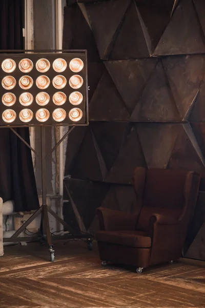 Sahne ışıkları perdelerin arka planında kahverengi bir koltuk.