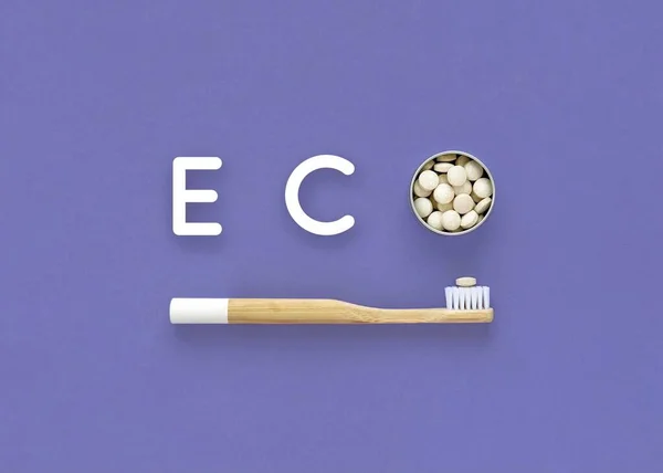 Bamboo toothbrush and toothpaste in tablets. Word Eco on a blue background. Very peri color. — Stock Photo, Image