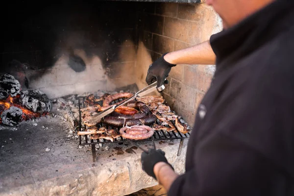 Homem na casa dos quarenta preparando um churrasco lançando a comida com diferentes tipos de carne — Fotografia de Stock