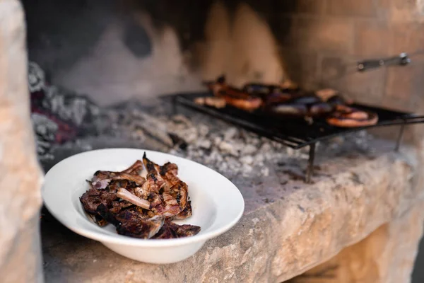 Барбекю приготовленное мясо сидит рядом с грилем барбекю с различными видами мяса. Закрыть. — стоковое фото