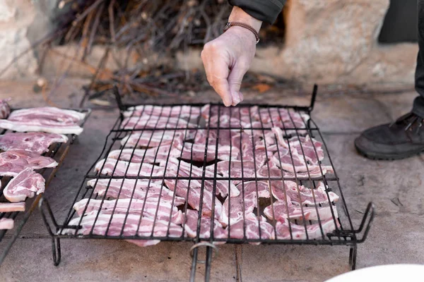 Неузнаваемый человек добавляет соль в сырое мясо в гриле перед приготовлением на барбекю. — стоковое фото