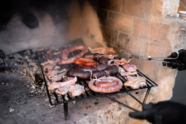 Hombre irreconocible usando las pinzas en una barbacoa de leña con diferentes tipos de carne. —  Fotos de Stock