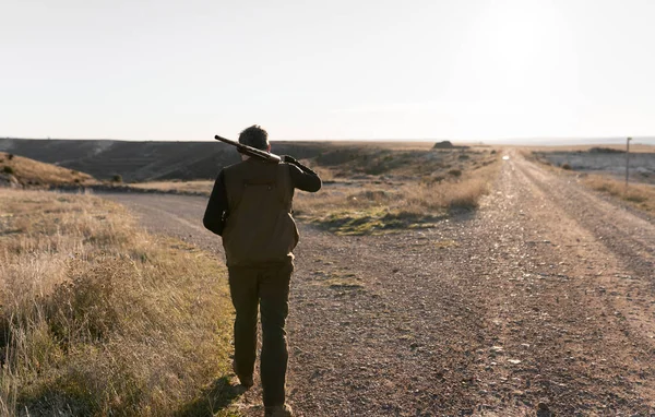 Hombre cazador está caminando con la escopeta en el hombro — Foto de Stock